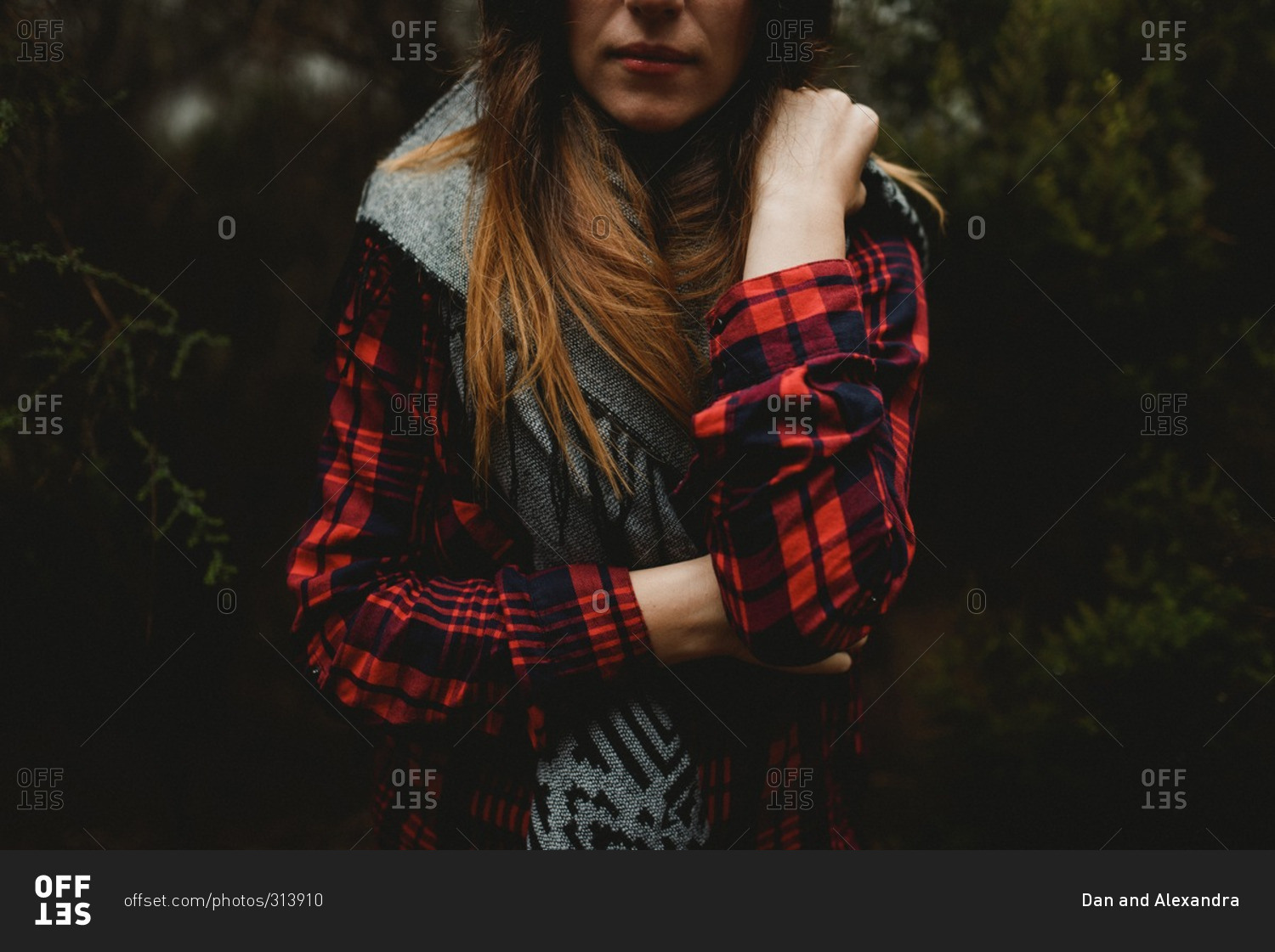 Young woman wearing a red flannel standing in the woods