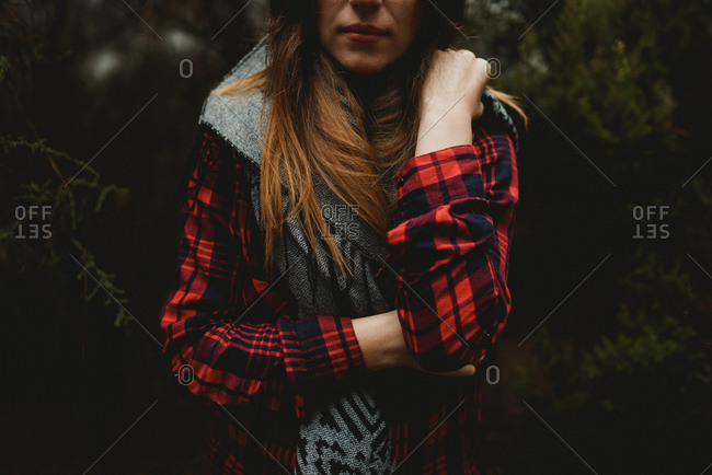 Young woman wearing a red flannel standing in the woods