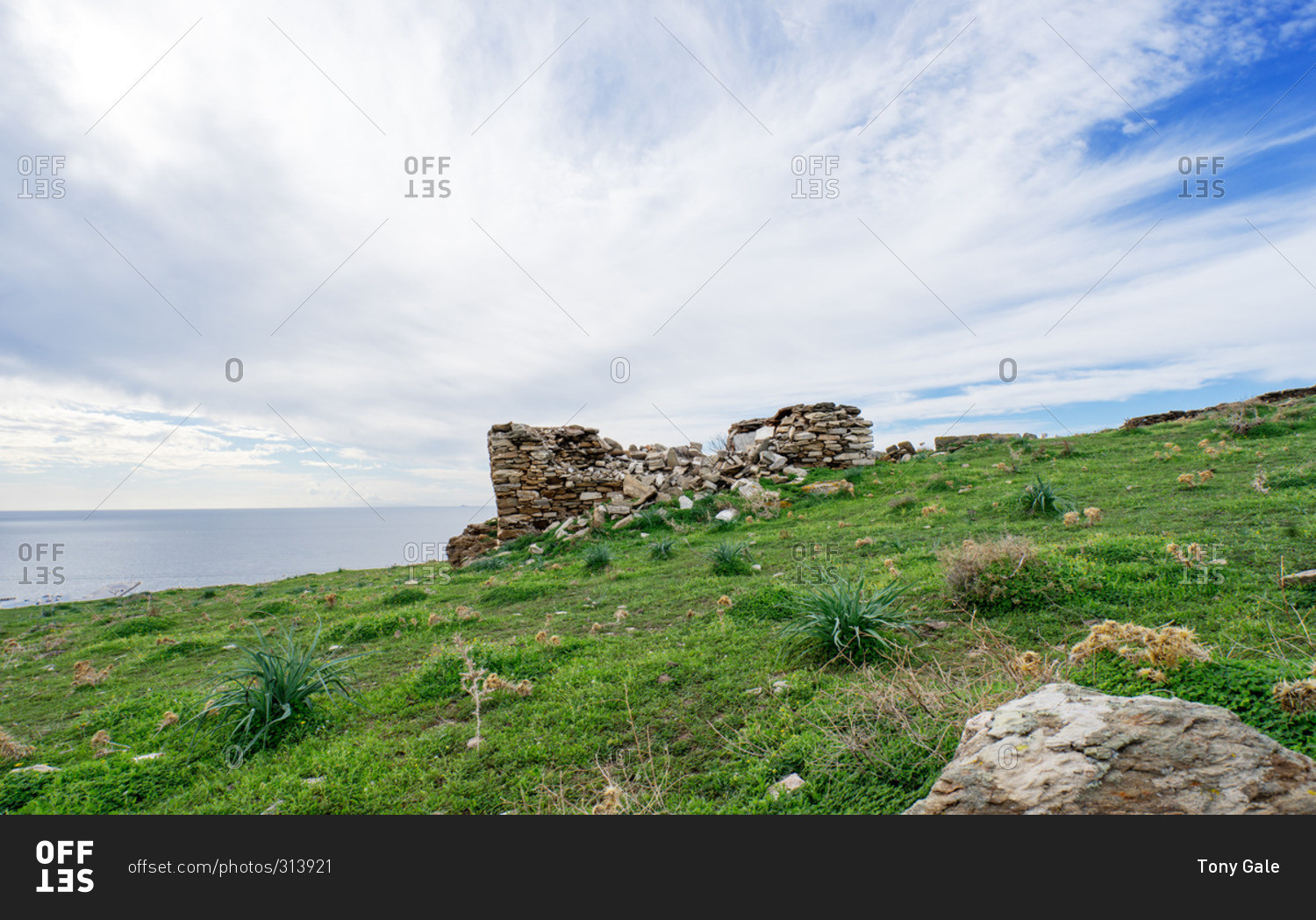 Crumbling stone foundation of house on hillside above the sea