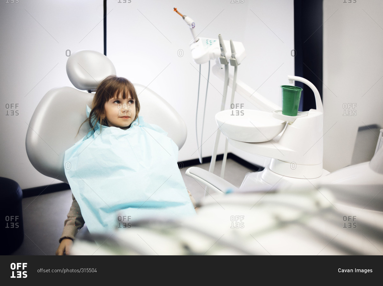 Girl wearing a dental bib sitting in dentist chair