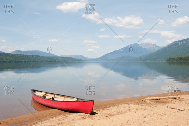 Canoe on a sandy beach at a pristine wilderness lake in the mountains
