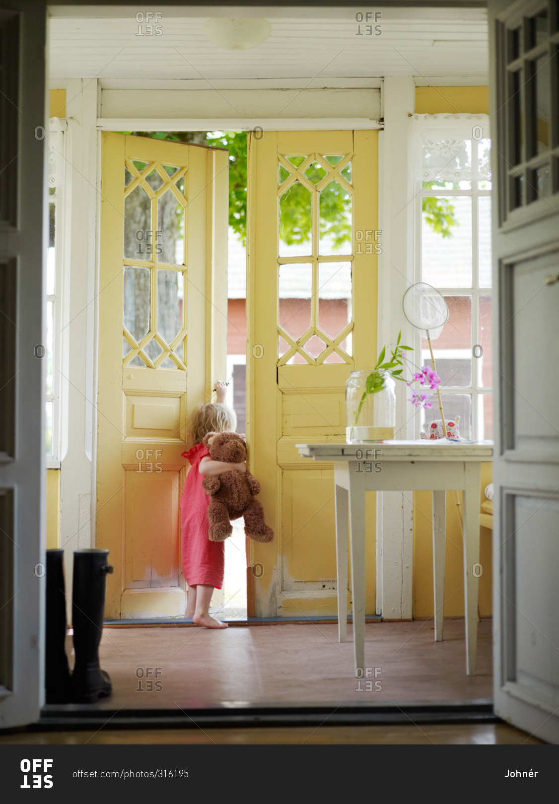 Girl with a teddy bear by a outer door