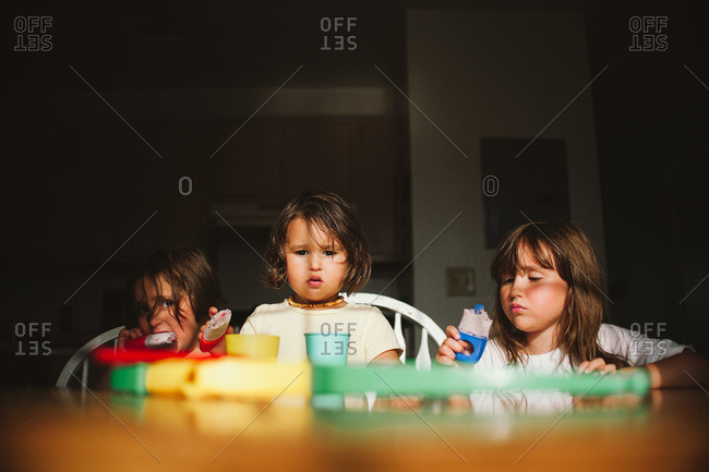 Three girls eating popsicles at table
