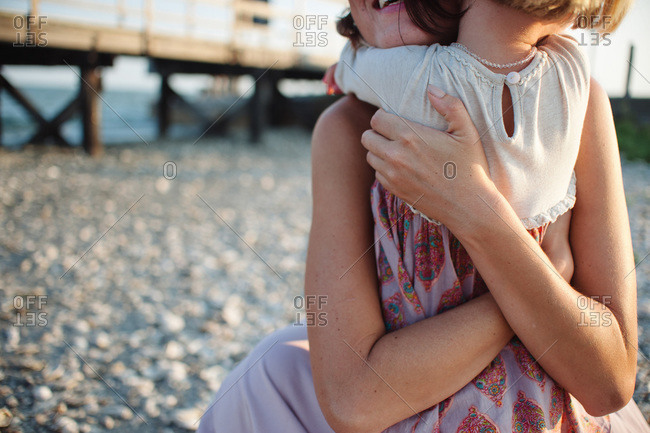 Mom holding girl tight on beach