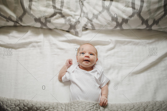 Newborn baby lying on a bed wide awake