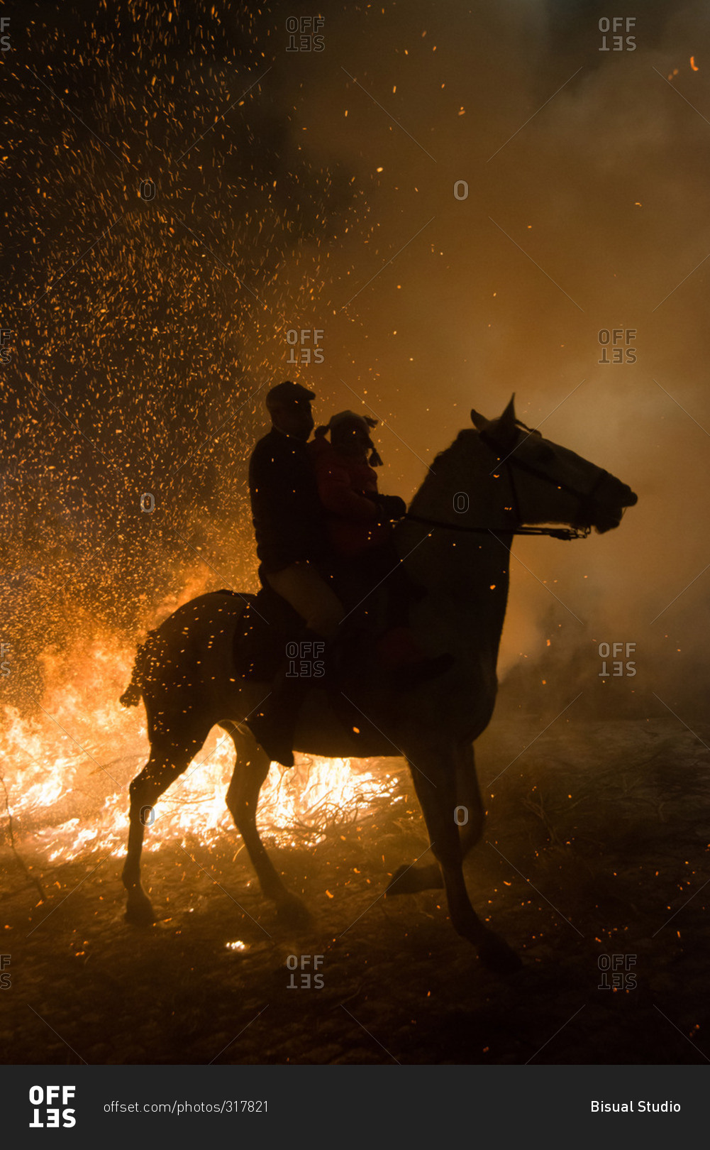 A man and a little girl ride a horse next to a bonfire during 'Las Luminarias' Festival. In honor of Saint Antony, the patron saint of animals, horses are ridden through the bonfires to purify and protect the animal during the year ahead
