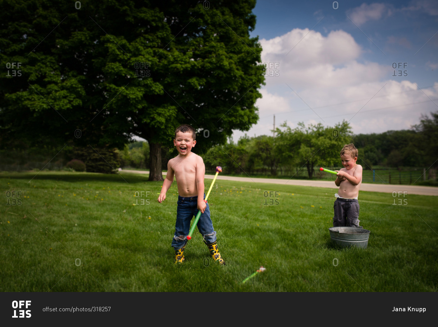 Two boys playing with water toys in the yard during the summer stock ...