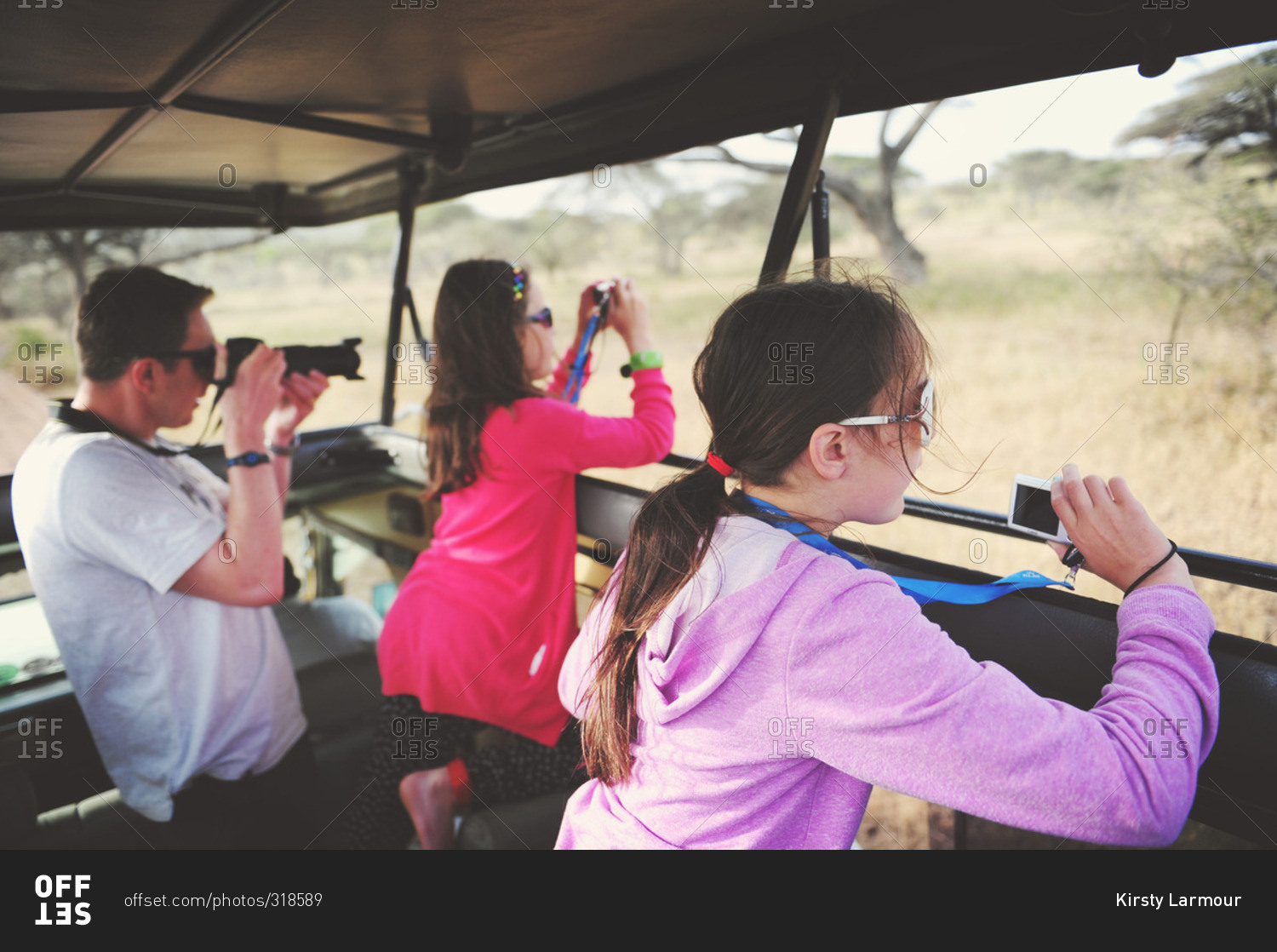 Father photographing wildlife with his daughters on safari in the African Serengeti