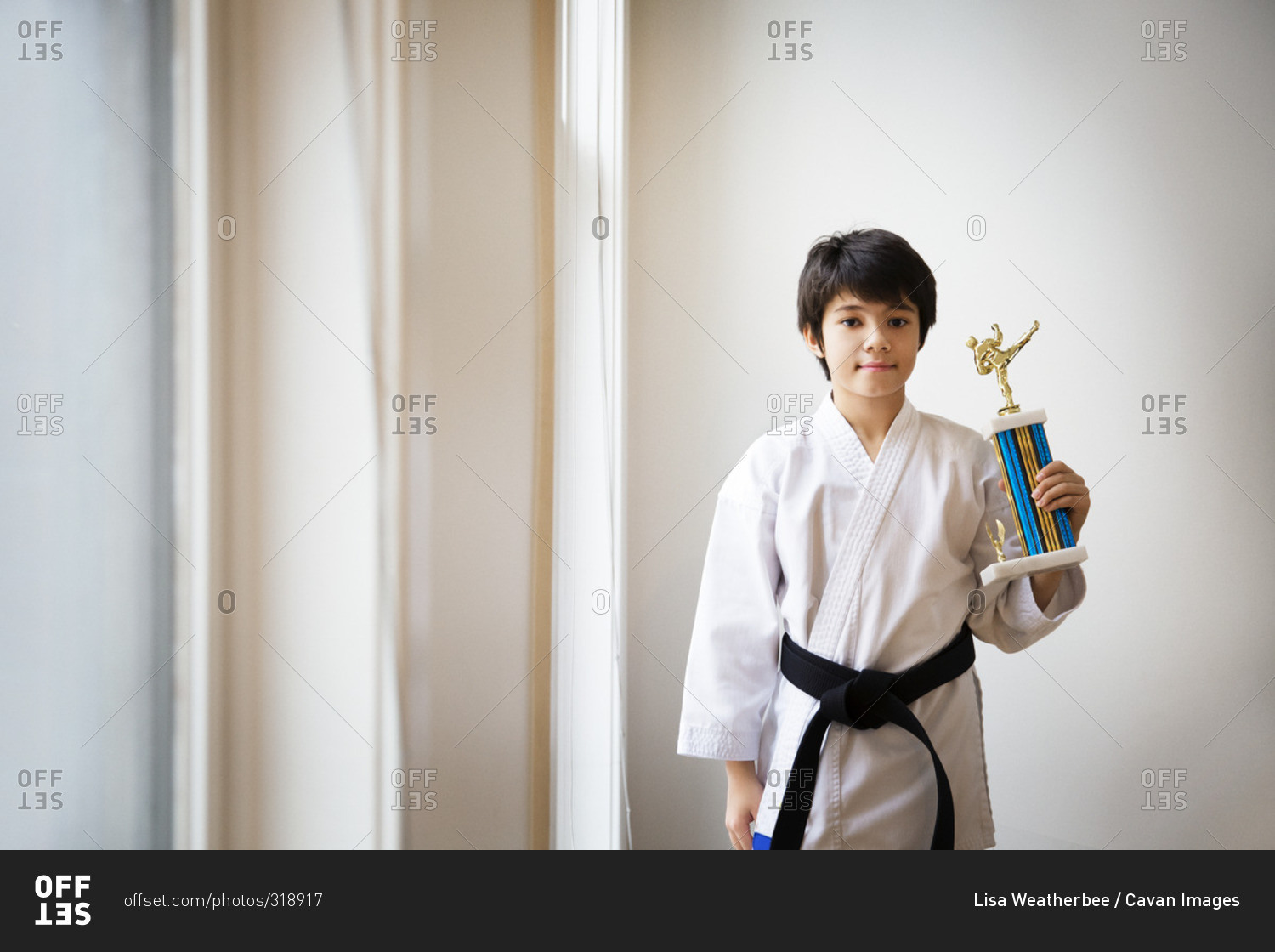 Boy in martial arts outfit with trophy