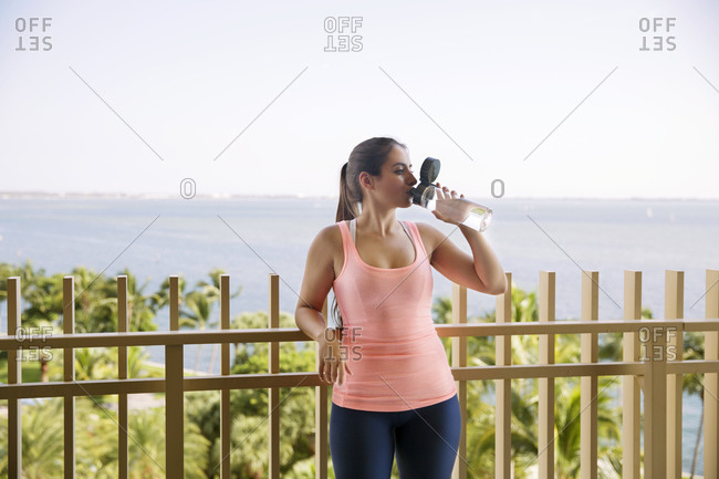 Woman hydrating on ocean view deck