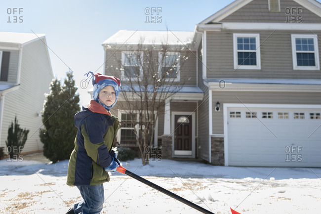 Little boy shoveling snow in his front yard