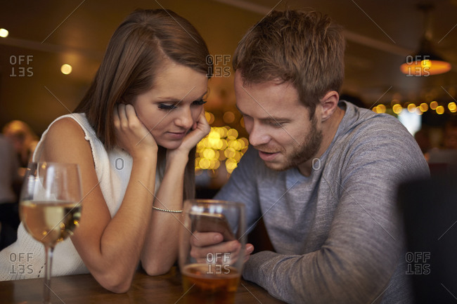 Romantic couple sitting and talking in wine bar together stock photo -  OFFSET