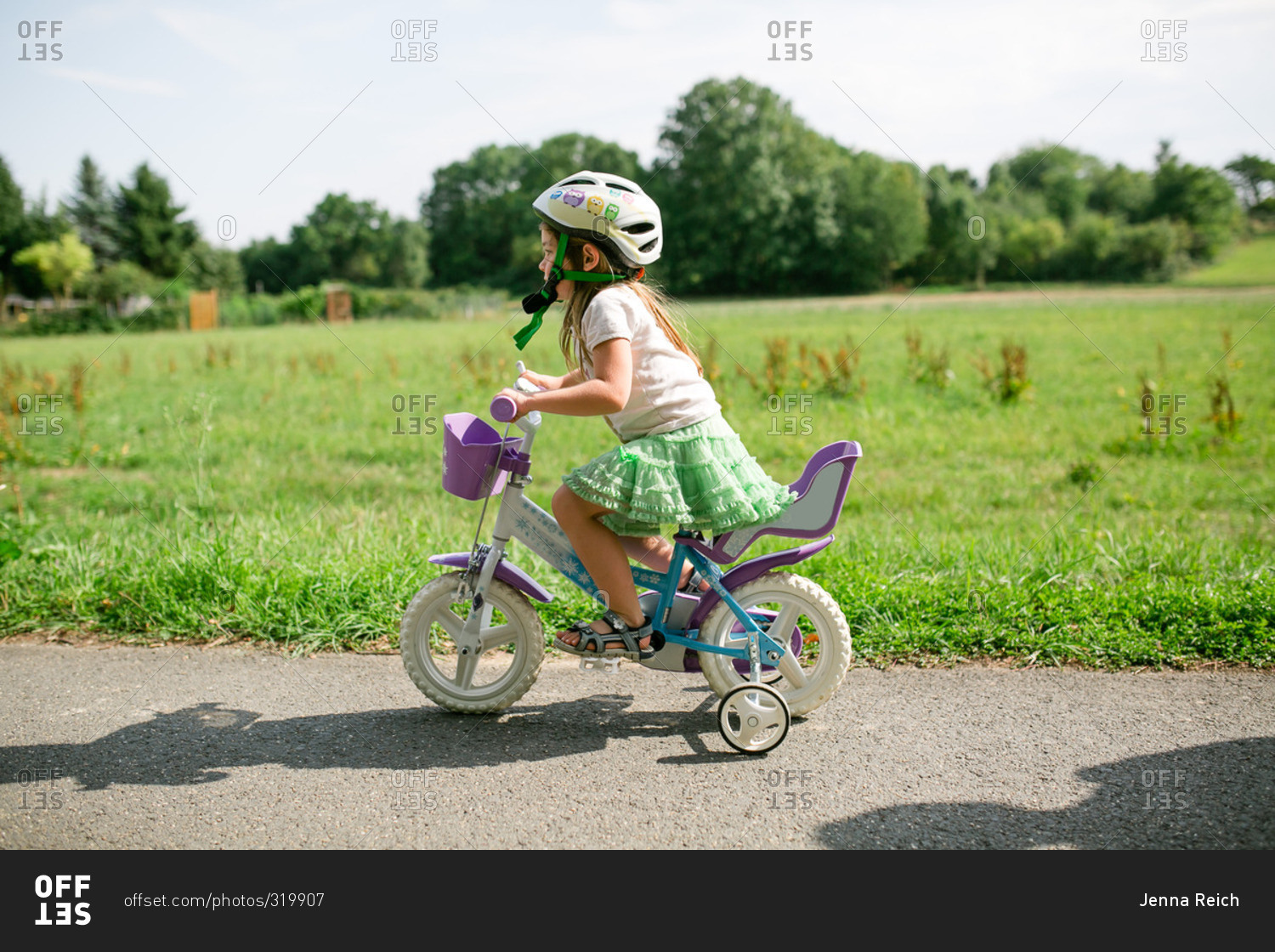Little girl riding a bike with training wheels