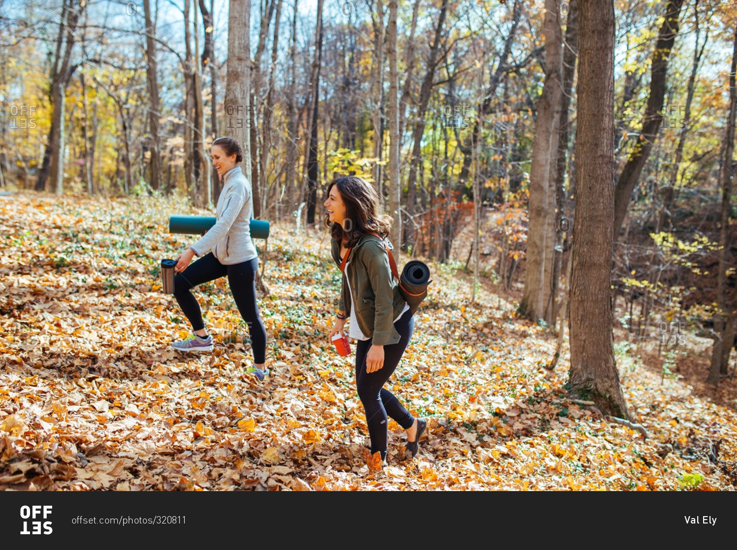 Women carrying their yoga mats in autumn woods for workout