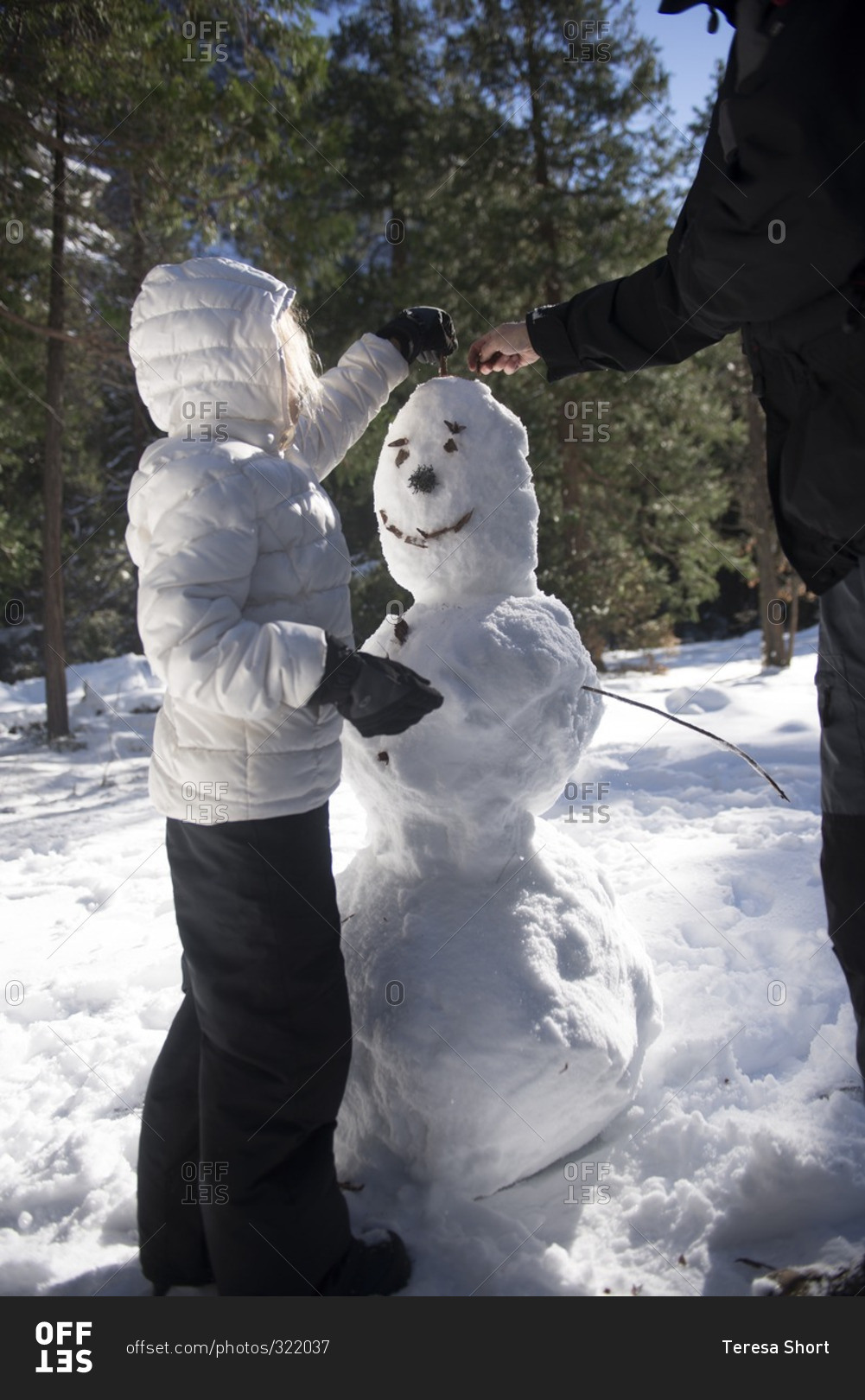 Father and daughter adding hair to a snowman