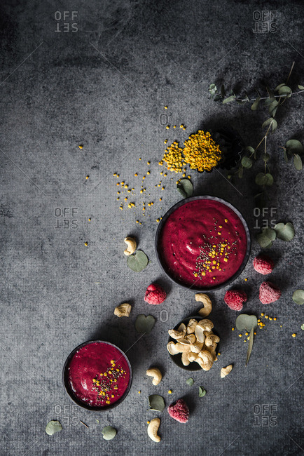 Overhead view of raspberry coulis with cashew nuts garnished with herbs