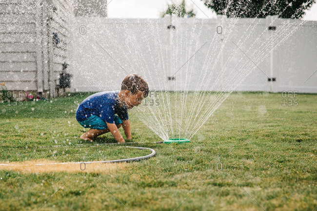Boy playing with a sprinkler in the yard