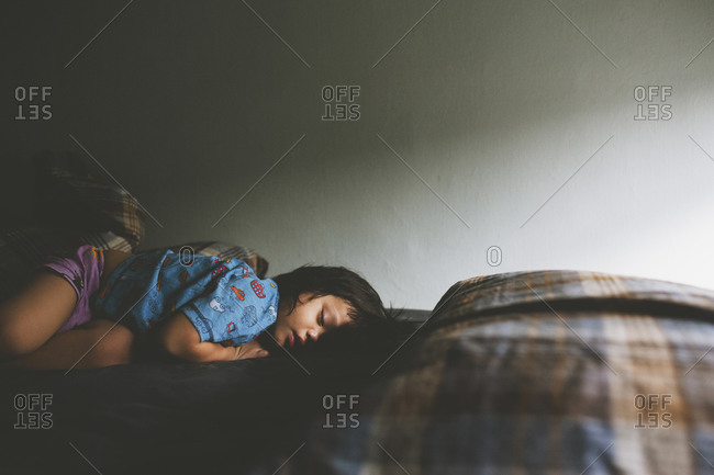 Young boy napping on his bed