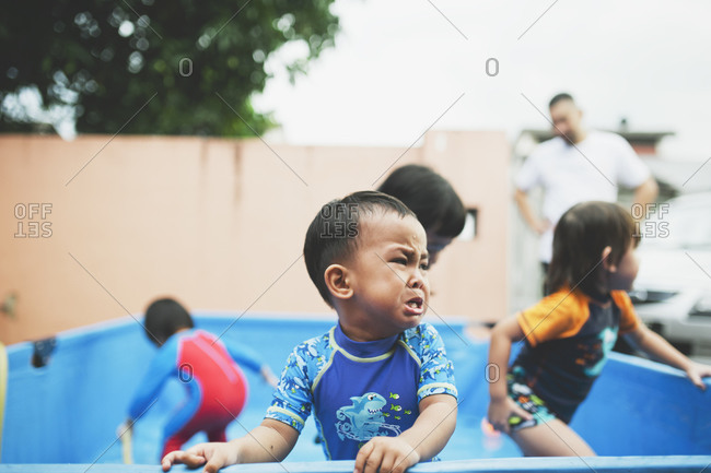Boy upset in pool near children