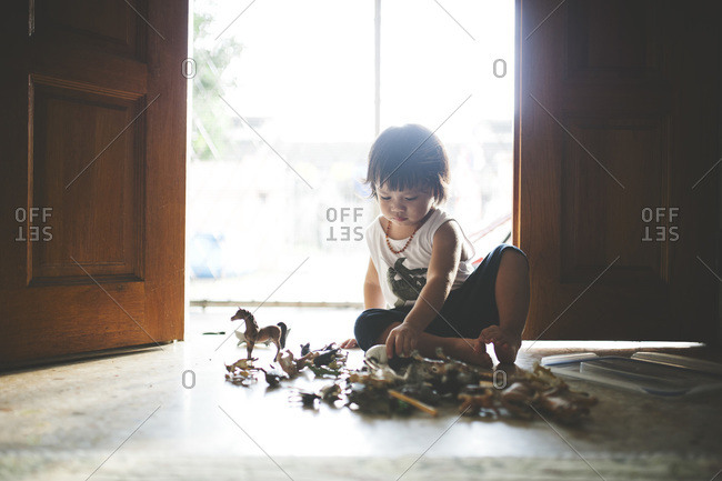 Boy in sunlight by door with toys