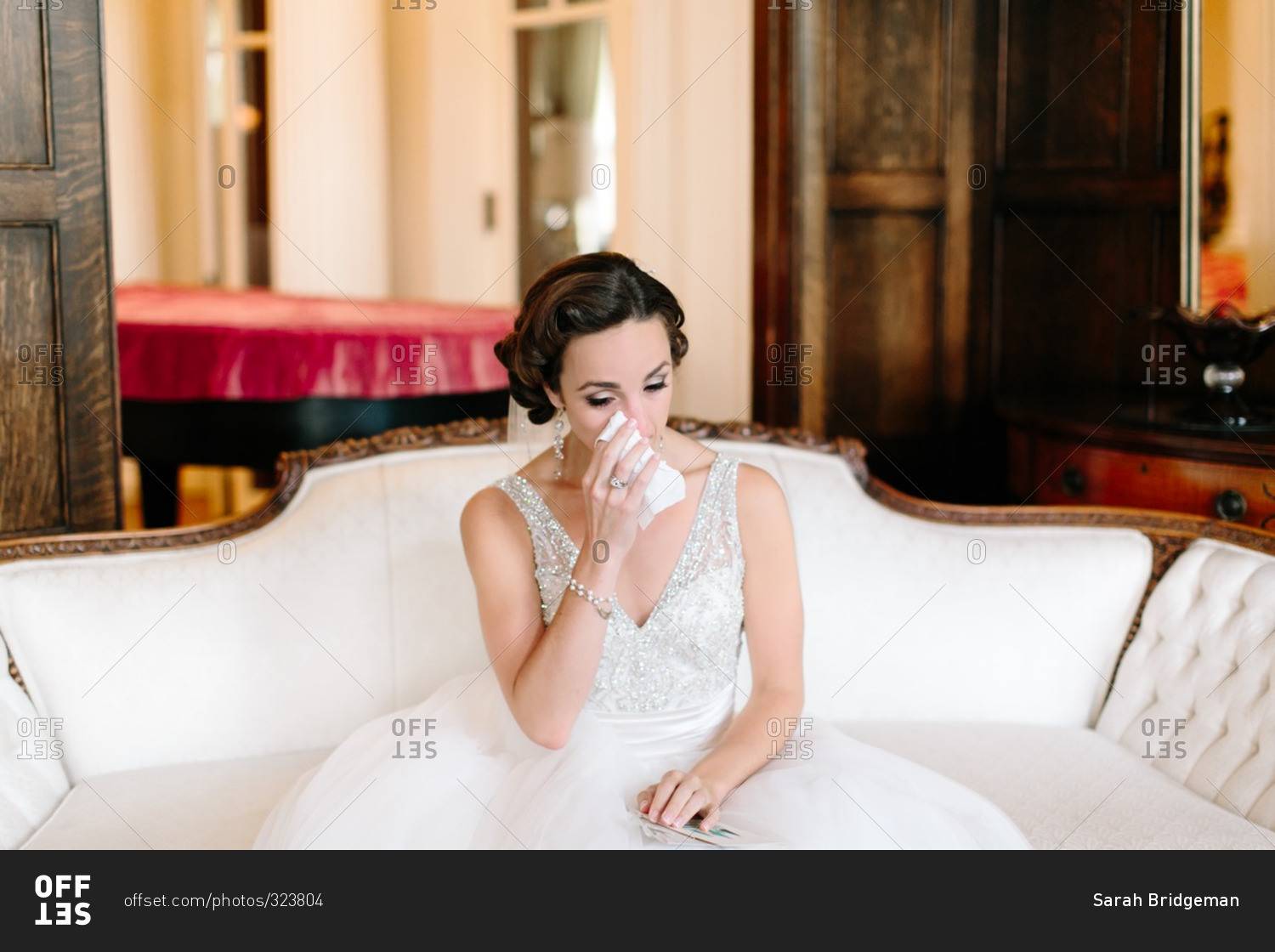 Bride sitting on a white sofa crying