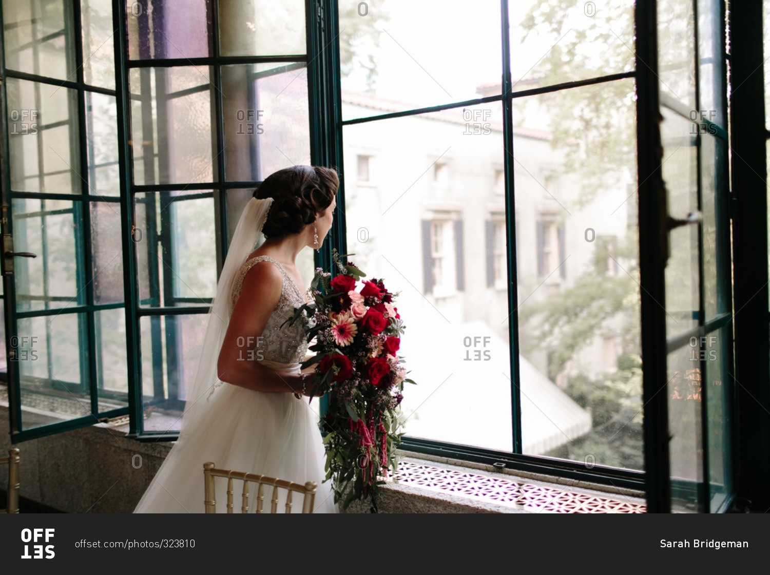 Bride holding a bouquet of flowers and looking out the window
