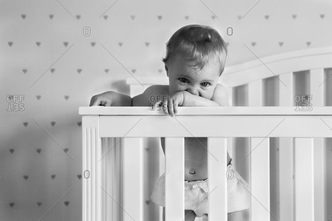 Baby girl standing in a crib crying