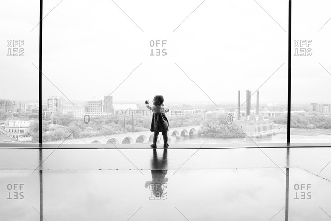 Silhouette of baby girl standing in front of a large window