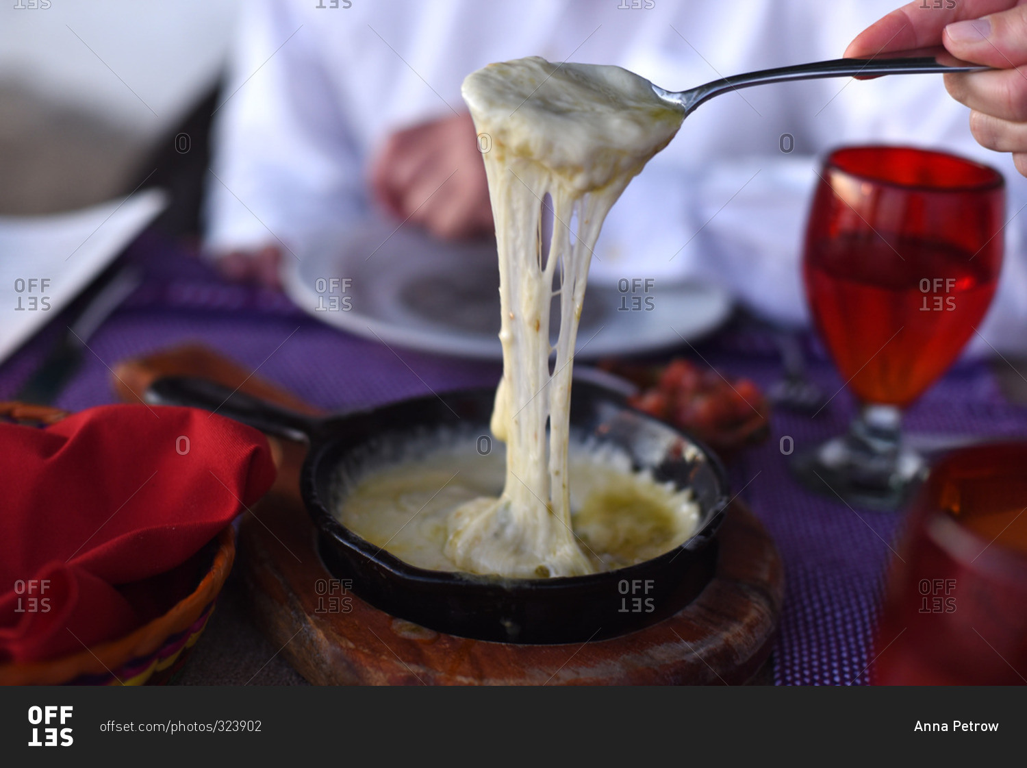 Person holding spoon full of melted cheese