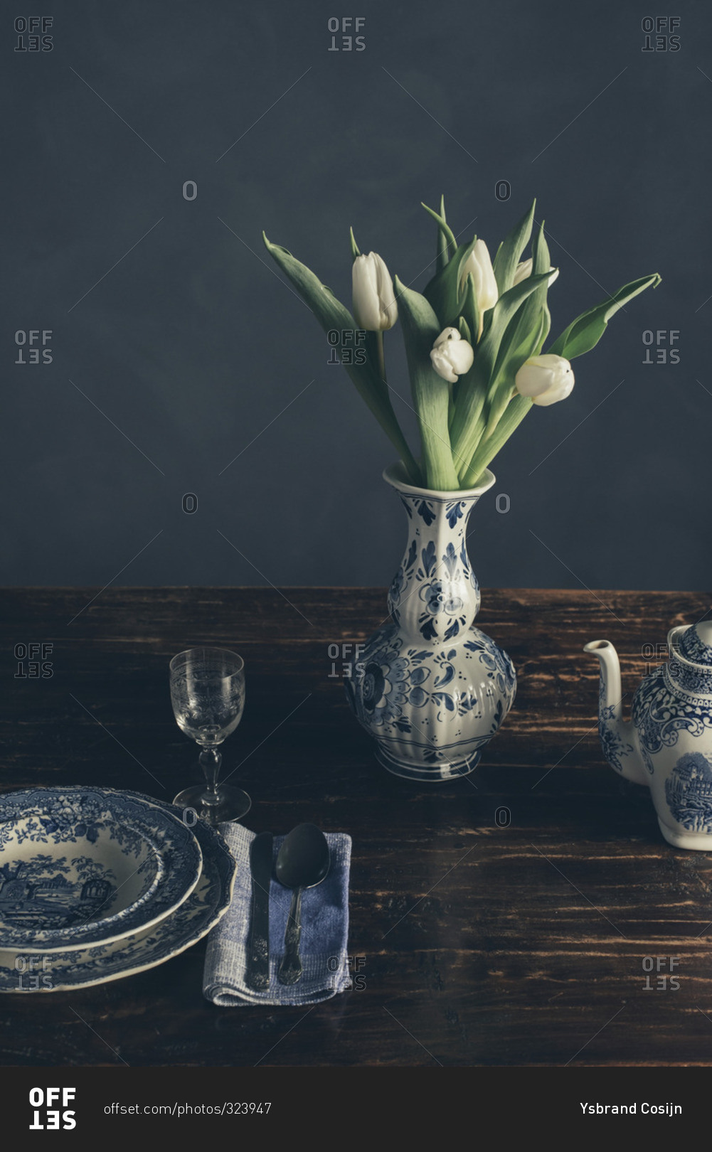 Still life of a vase of tulips and place setting on a wood table