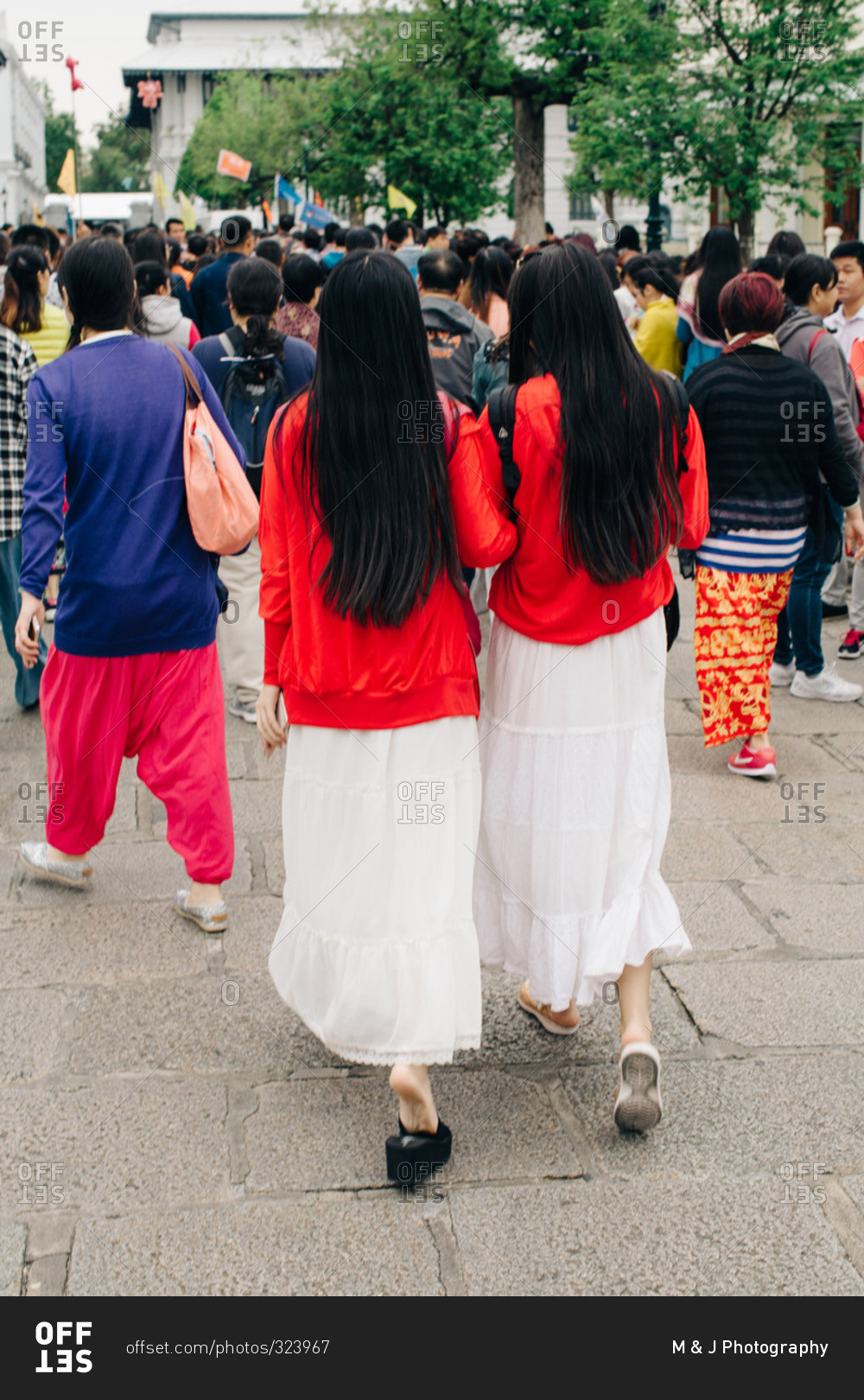 Two women walking through a crowd in the same outfit