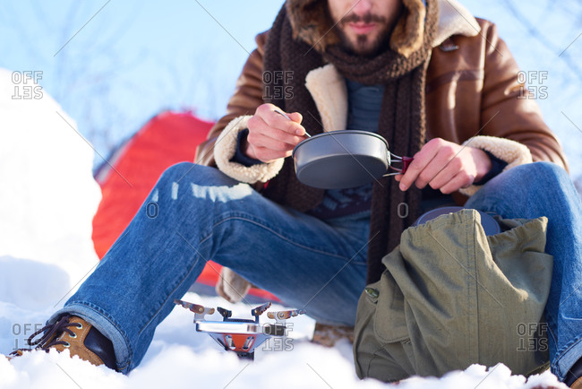 Man eating a meal cooked on a campstove in the snow