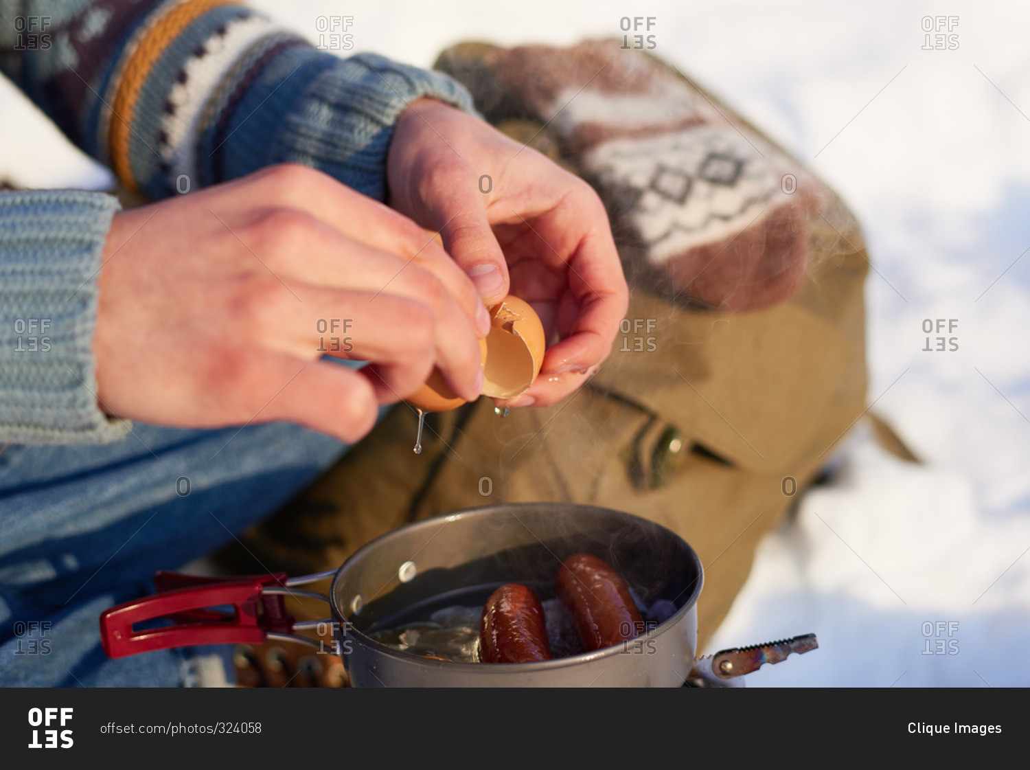 Man making eggs and sausages over a campstove in the snow