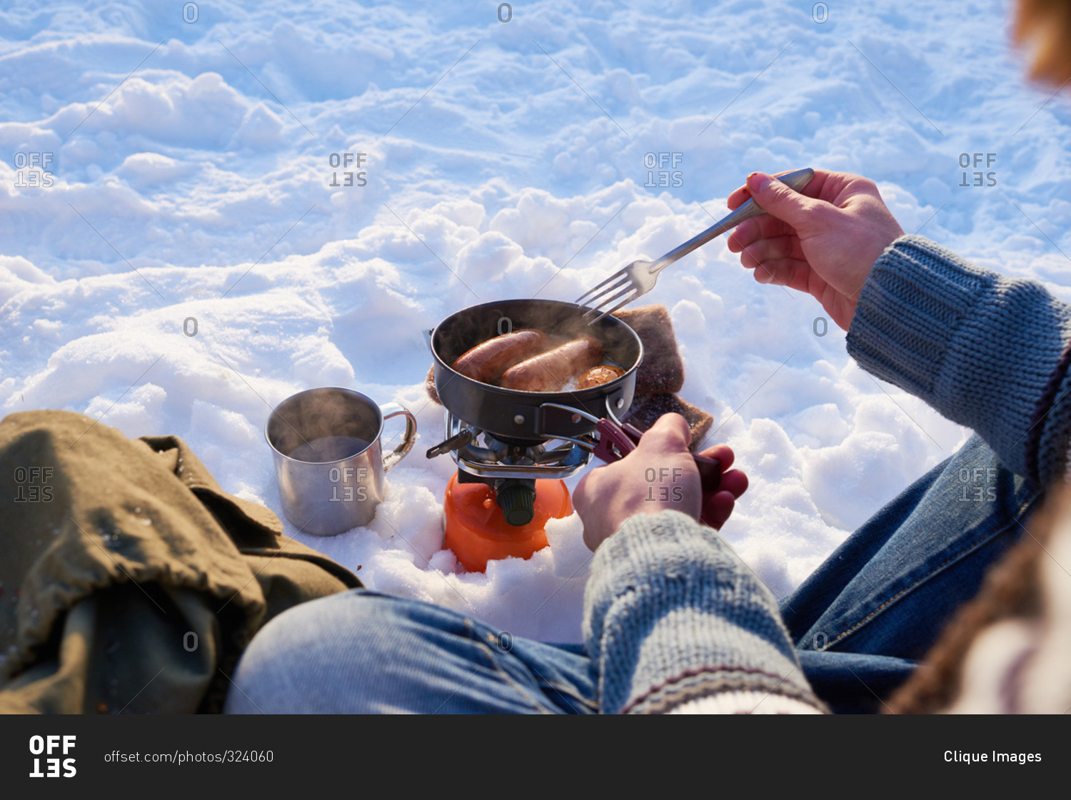 Man stirring sausages in a pot in the snow