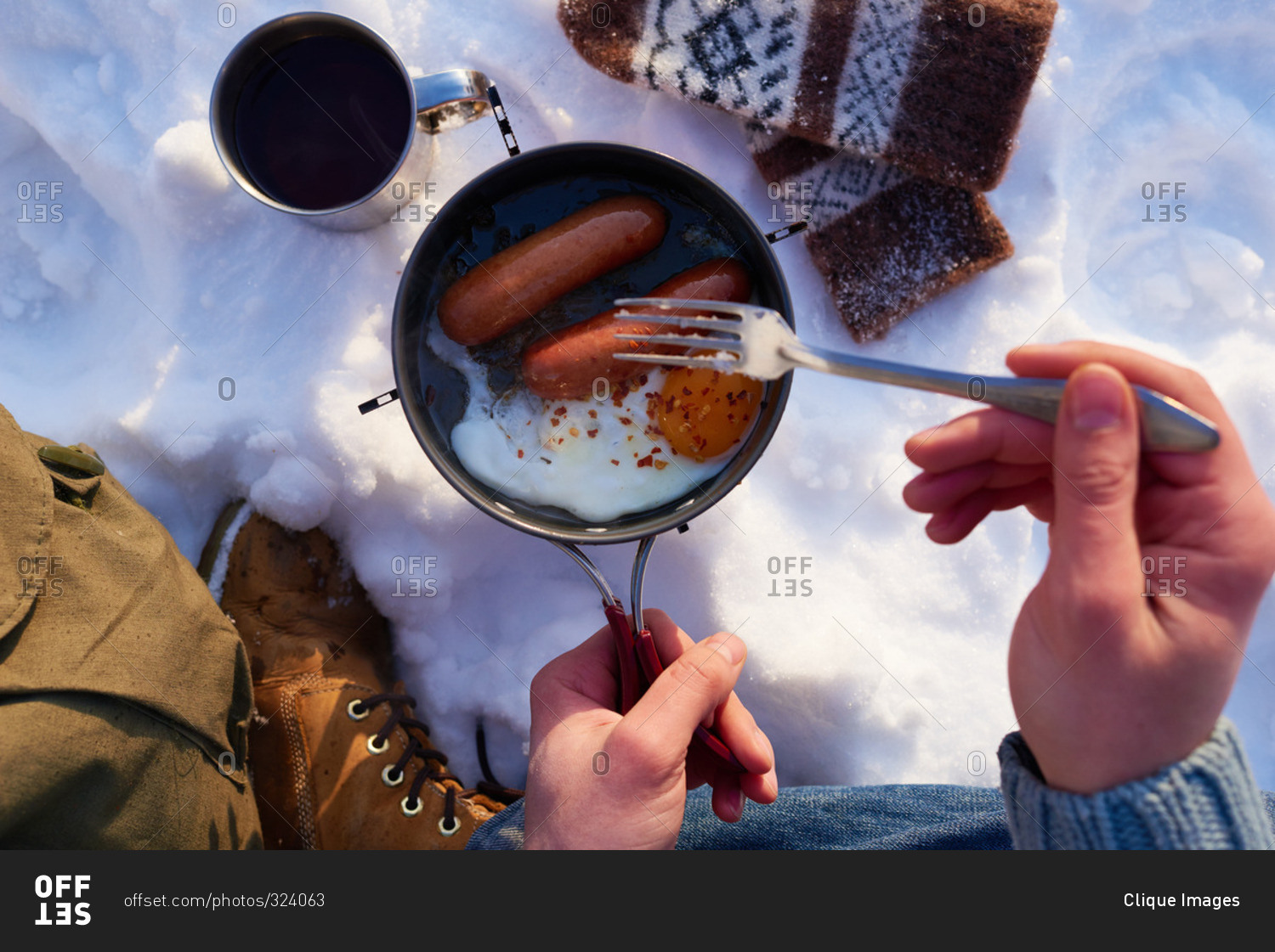 Man cooking sausages and eggs in the snow