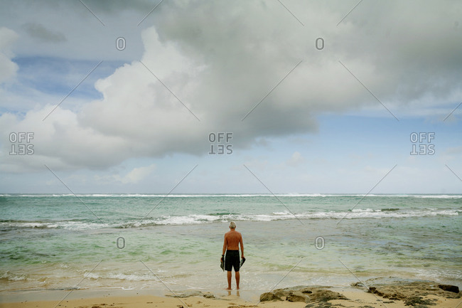 Senior man standing with flippers on a beach