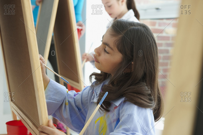 Student painting at easel in art class