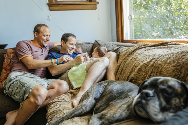 Gay Couple Playing With Baby Boy On Sofa Stock Photo Offset