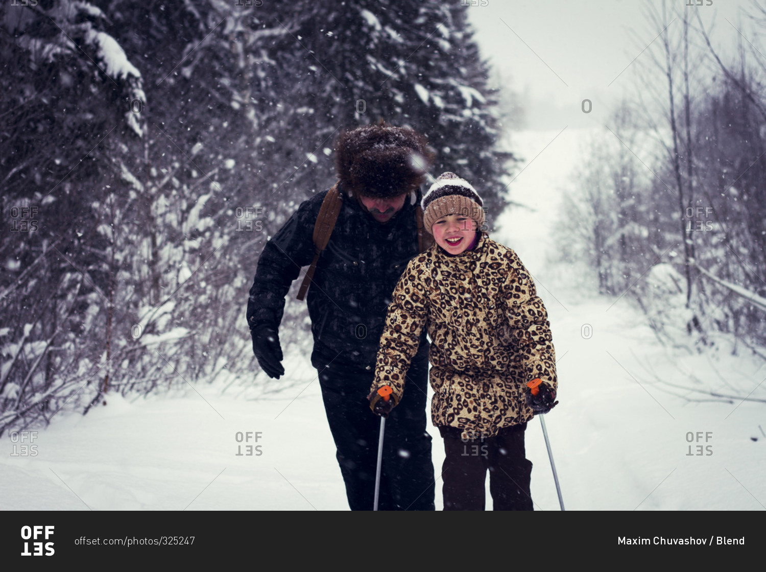 Father and daughter cross-country skiing on snowy road