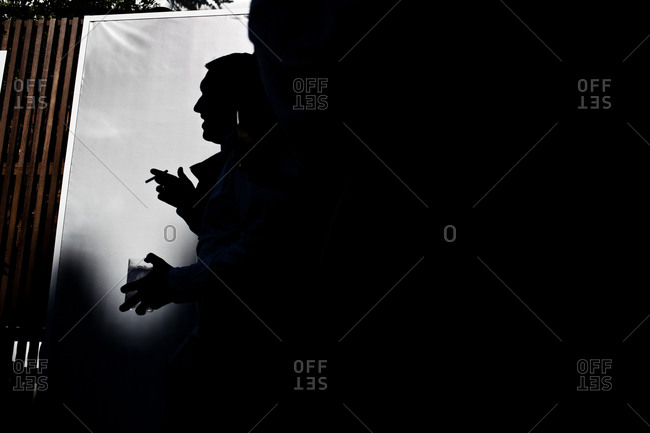 Silhouette of a man holding a drink and a cigarette