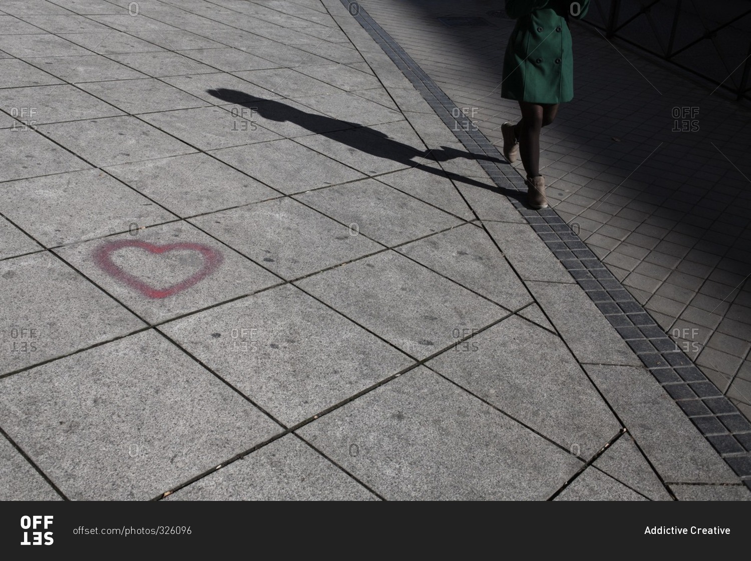 Woman walking down the sidewalk past a graffiti heart