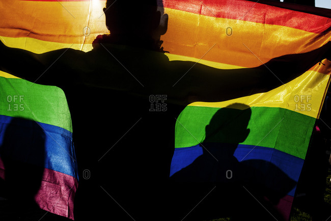 Silhouetted figures holding the rainbow LGBT pride flag