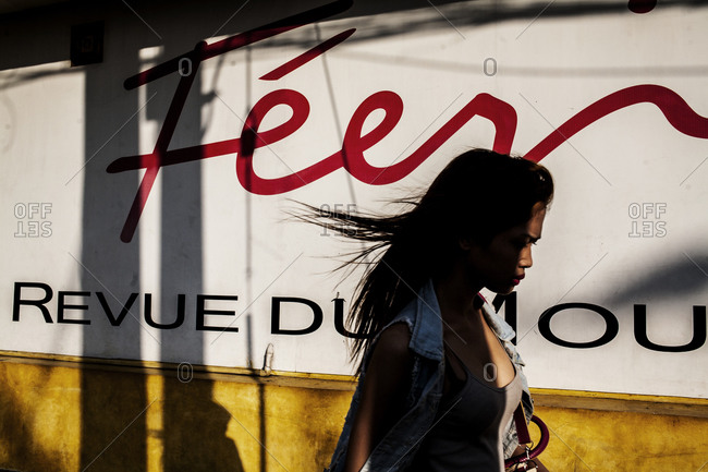 Woman walking in front of a sign on a city street