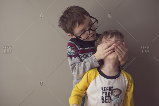 Boy covering the face of another boy with his hands