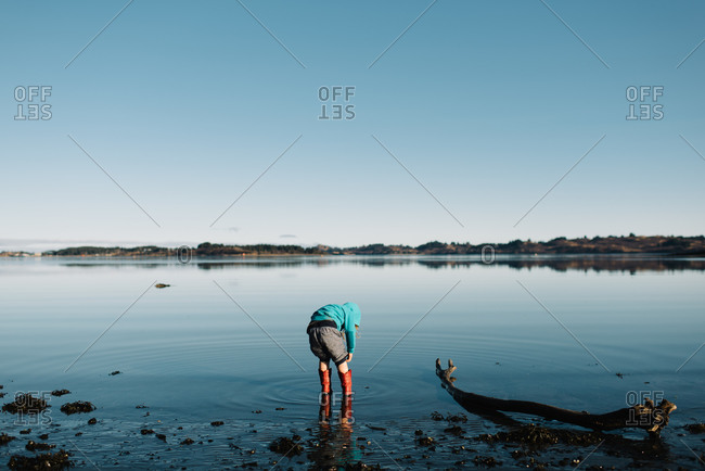 Kid standing in water in rain boots