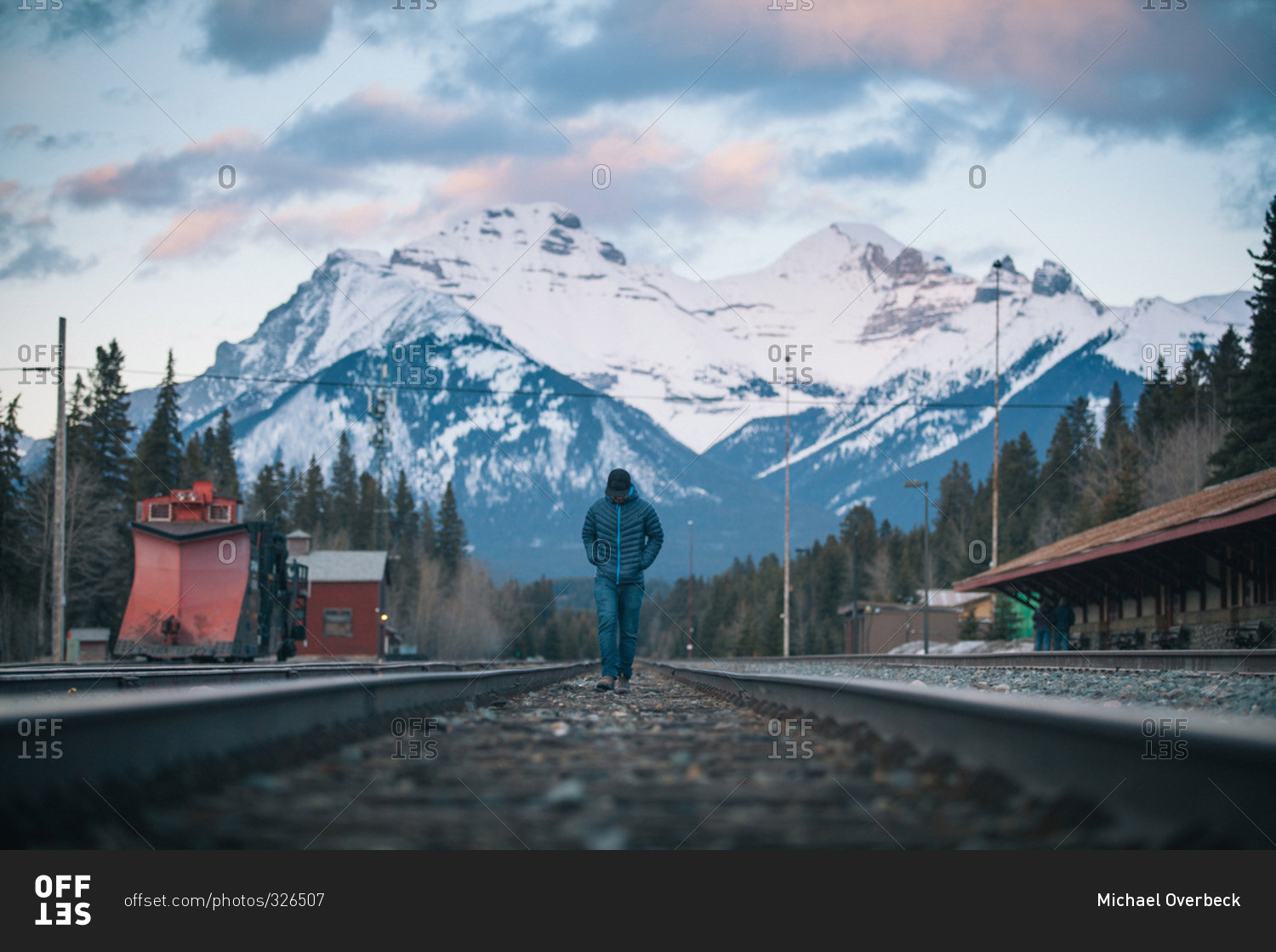 Man walking on train tracks in a mountain valley