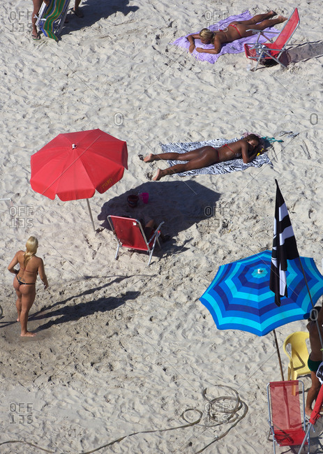 Woman lying on the beach without the bikini top looking at camera