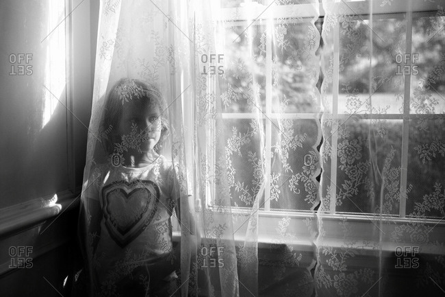 Woman wearing bra and panties looking through the window of her