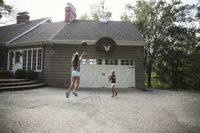Two girls playing basketball in their driveway