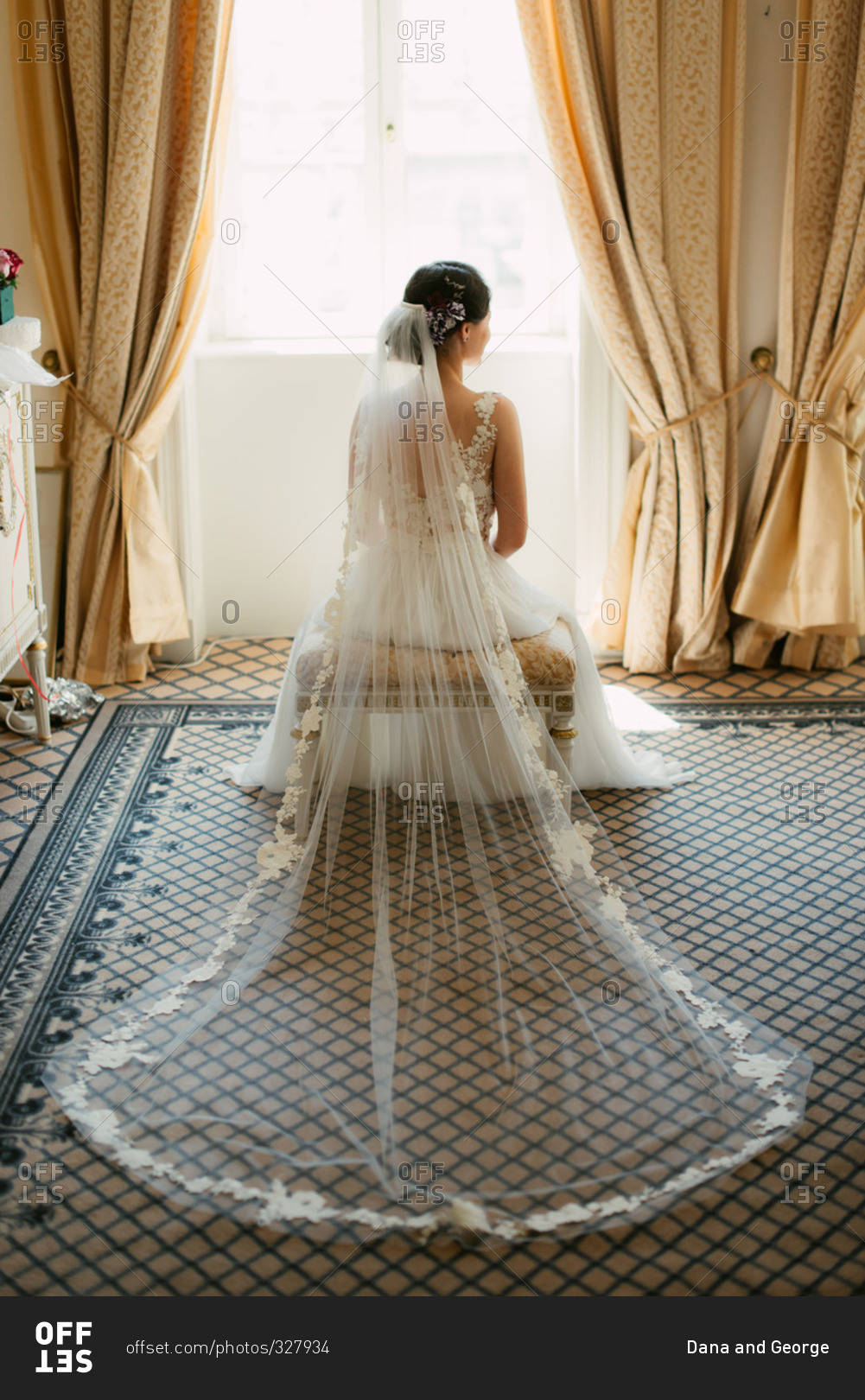 Back view of elegant seated bride with veil spread out behind her